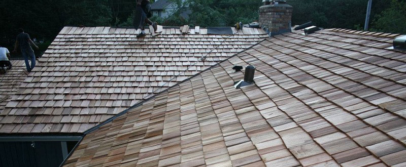 Cedar roofing installation in progress, showcasing newly laid shingles and construction workers on a sloped roof, emphasizing Pineview Builders' commitment to quality home construction in the Twin Cities.