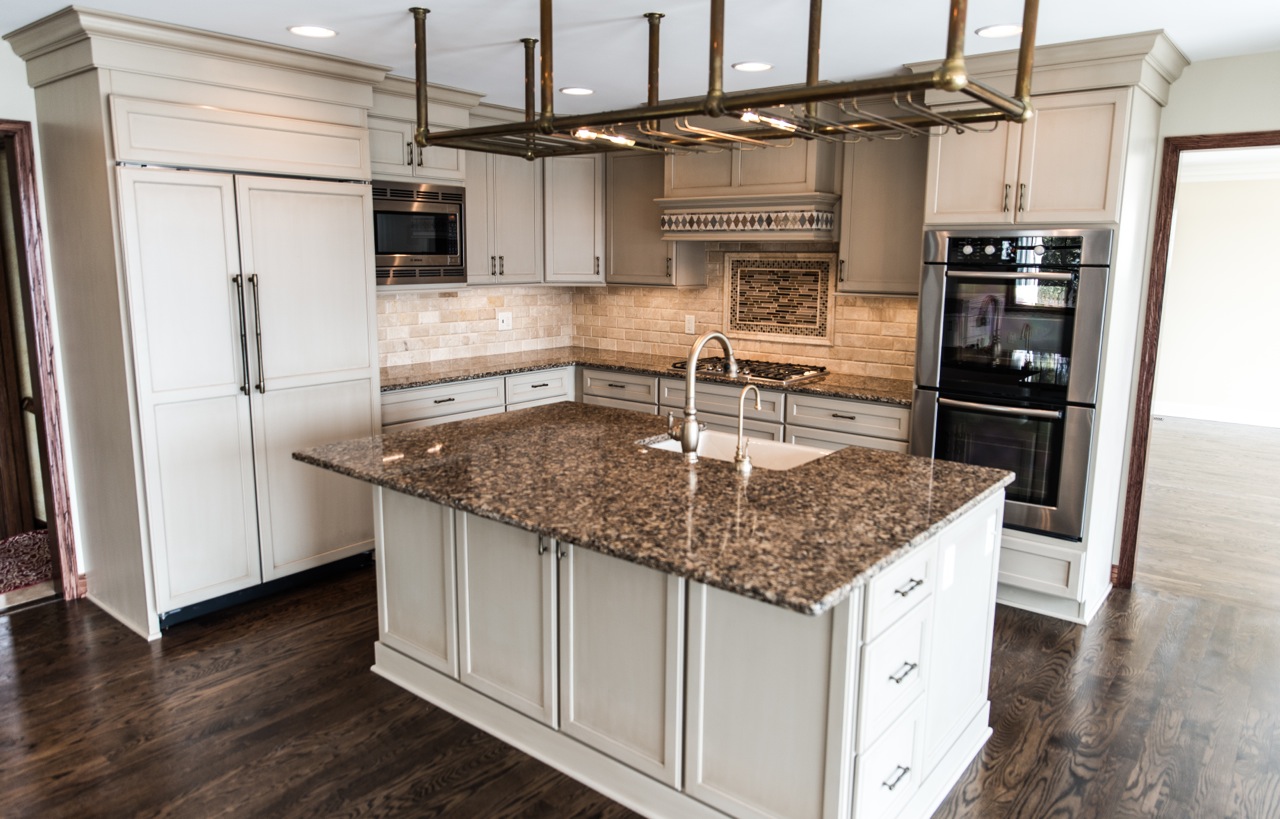 Remodeled kitchen featuring elegant cabinetry, granite island, exposed brick backsplash, and modern appliances, showcasing timeless design and functionality for home upgrades in the Twin Cities.