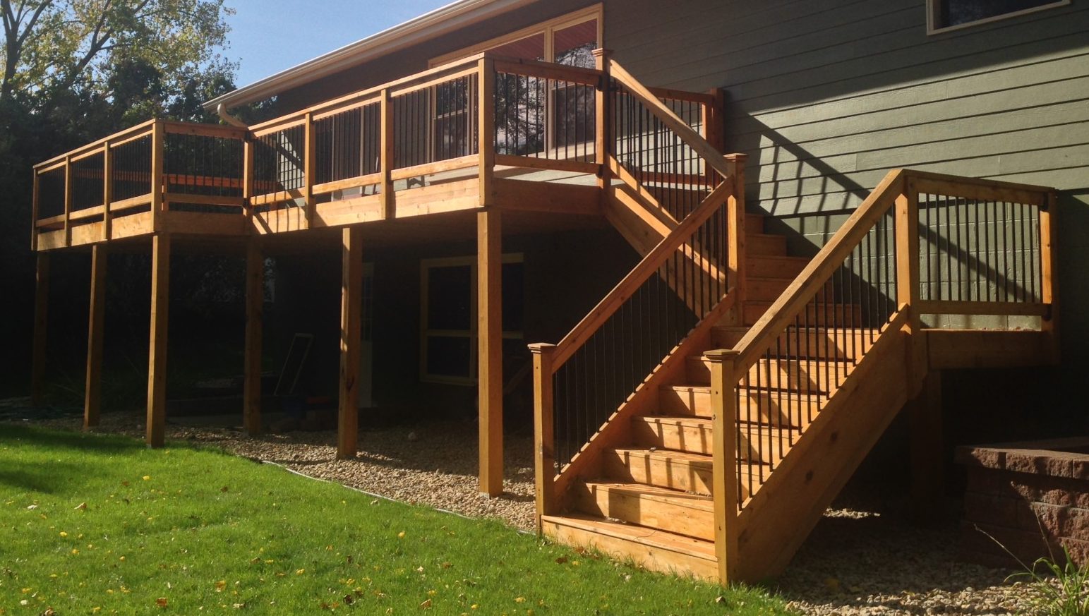 Wooden deck with railing and stairs, showcasing quality construction by Pineview Builders, surrounded by green lawn and trees, emphasizing residential outdoor living space.